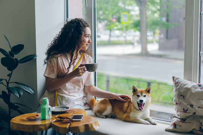a woman sitting on a window sill next to a dog